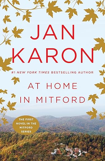 Book cover for At Home in Mitford shows small town nestled amid mountains and trees beneath a blue sky